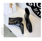 Foto artística de botas pretas texturizadas deitadas e em pé junto a uma caixa de presente