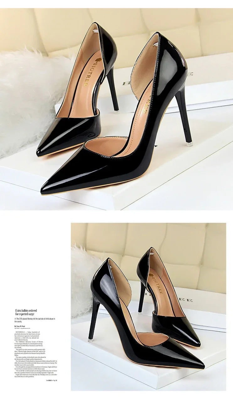 Glänzende schwarze pointed-toe Pumps mit Seitenausschnitt auf weißer Box mit Zeitschrift als Deko, reflektierendes Material im Fokus