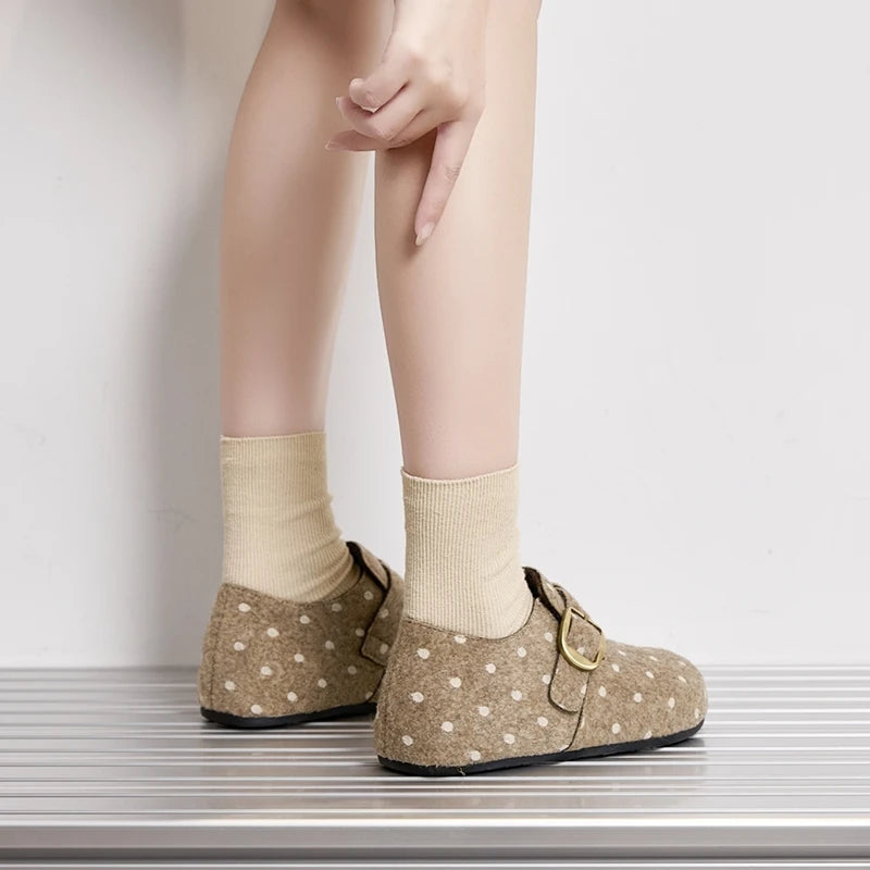 Vista trasera de mujer con zapatillas slip-on beige con lunares y hebillas doradas
