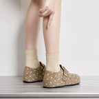 Vista trasera de mujer con zapatillas slip-on beige con lunares y hebillas doradas