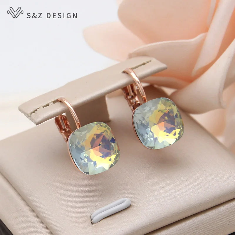 Brincos de pressão dourado-rosé com cristais grandes iridescentes azul, amarelo e roxo no suporte bege S&Z DESIGN