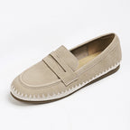 Mocassino slip-on beige chiaro focalizzato sulla texture pelliccia dell'upper e sul dettaglio strutturato della tracolla da penny loafer