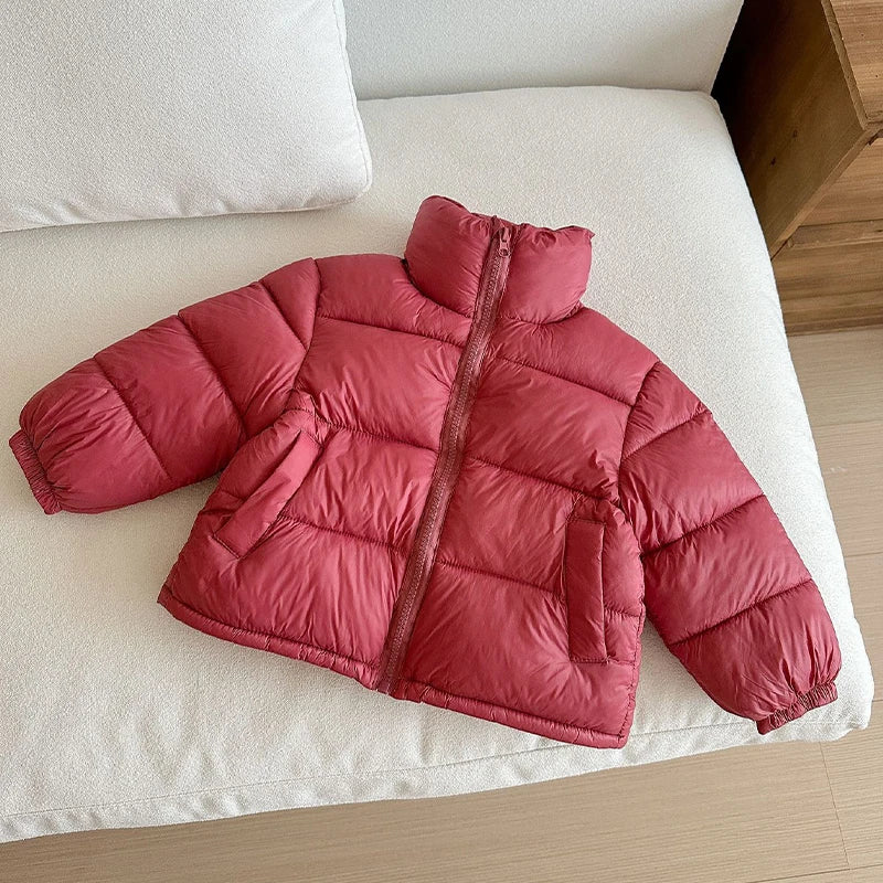 Deep red berry colored puffer jacket flat lay on white cushion showing high collar, zipper, and horizontal stitching.