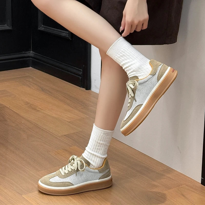Dynamic side angle of sneaker silhouette with smooth gum sole as model lifts foot for walking fit