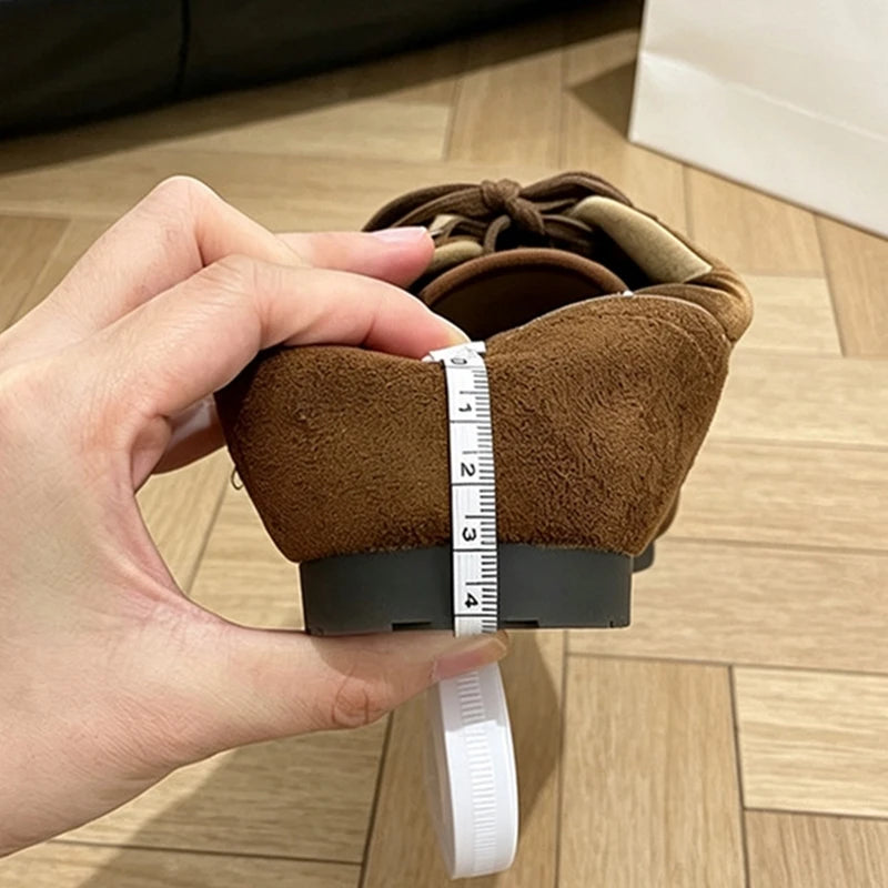 White tape measure wrapped around the heel circumference of a brown sneaker on wooden floor