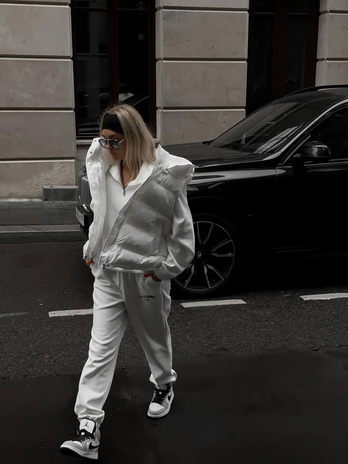 Foto corporal ao ar livre de modelo a caminhar com colete acolchoado branco em rua molhada