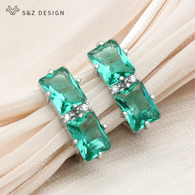 Brincos pendentes em tom de prata com cristais facetados verde-esmeralda vibrantes conectados por banda de cristal claro