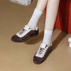 Par de zapatillas retro de cuero y ante marrón oscuro usadas con calcetines blancos acanalados cerca de mueble rojo