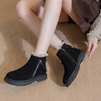 Botines de ante negro con tira de cuero para la cremallera, forro crema y suela rugosa de goma usados por modelo sentada