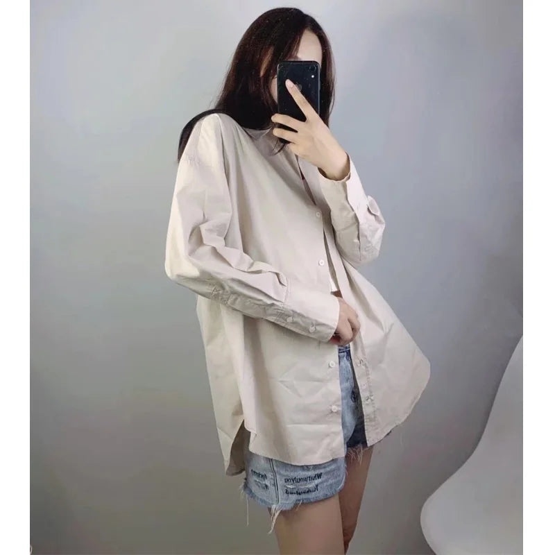 Vista laterale di camicia bottoni beige indossata aperta sopra shorts denim mostrando caduta e versatilità