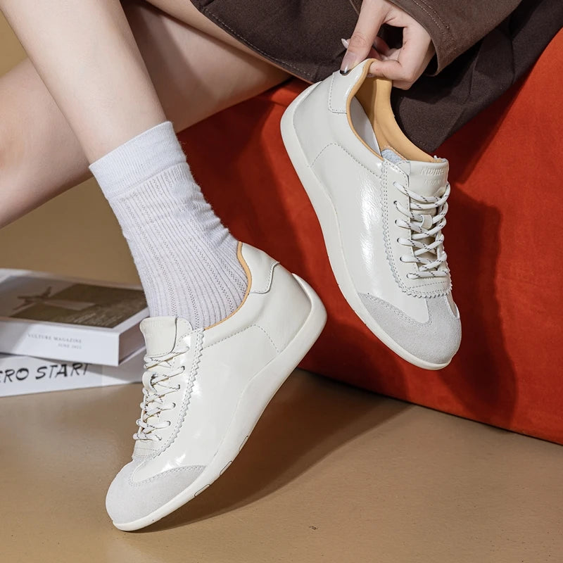 Zapatillas patchwork crema-blanco con puntas de ante gris usadas con calcetines acanalados sobre superficie de terciopelo naranja