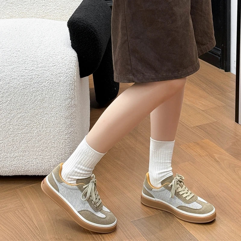 Model walking in earth-tone mesh and suede sneakers paired with white crew socks and brown skirt