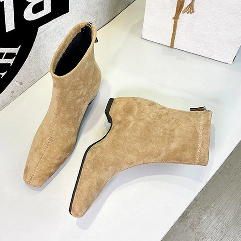 Tan-farbene Wildlederschnürsenkel-Stiefel mit quadratischer Spitze, schwarze Gummisohle sichtbar auf weißem Tisch.