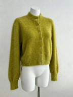 Cardigan longo de pelúcia verde oliva em manequim branco com material felpudo macio, punhos canelados e botões verticais