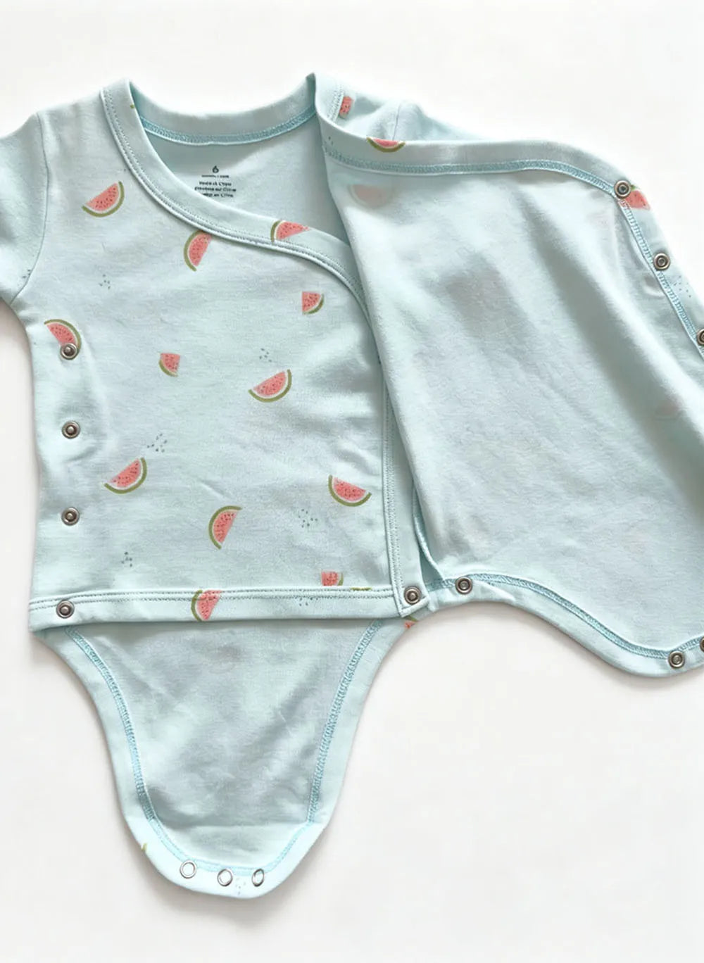 Top-down flat lay of short-sleeve romper with diagonal side-button opening and silver metal snaps