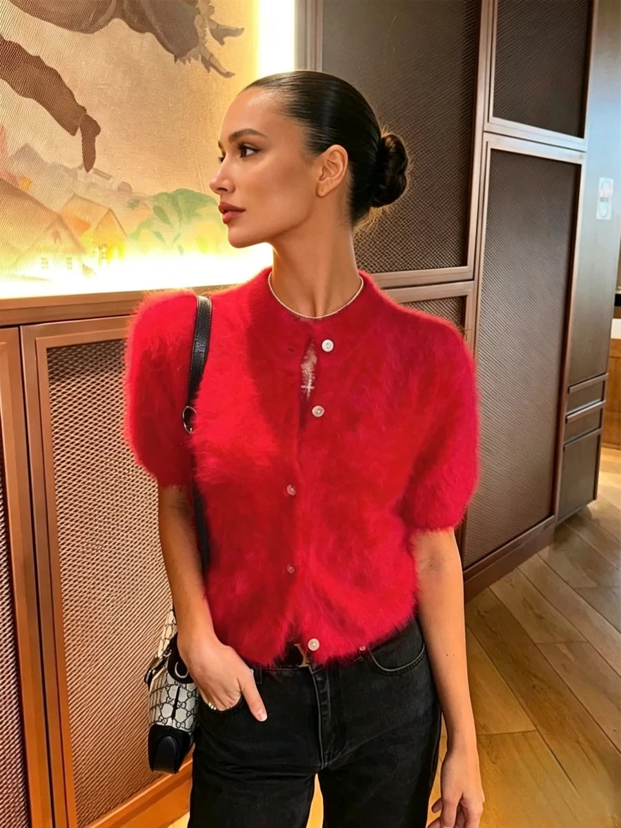 Perfil lateral de modelo com cardigan curto felpudo vermelho vibrante com gola redonda e botões claros, combinado com jeans pretos