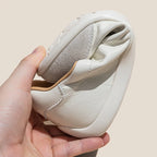 Mano doblando zapatilla blanca para mostrar flexibilidad, revelando parte superior de cuero dividido y suela gris texturizada
