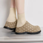 Rückansicht des Modells in beige Punkt-Mules betont das rückfreie Slip-On-Design und den Kontrast zwischen weichem Filz und Gummi