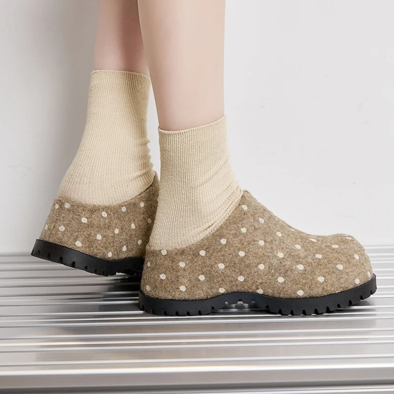 Rückansicht des Modells in beige Punkt-Mules betont das rückfreie Slip-On-Design und den Kontrast zwischen weichem Filz und Gummi