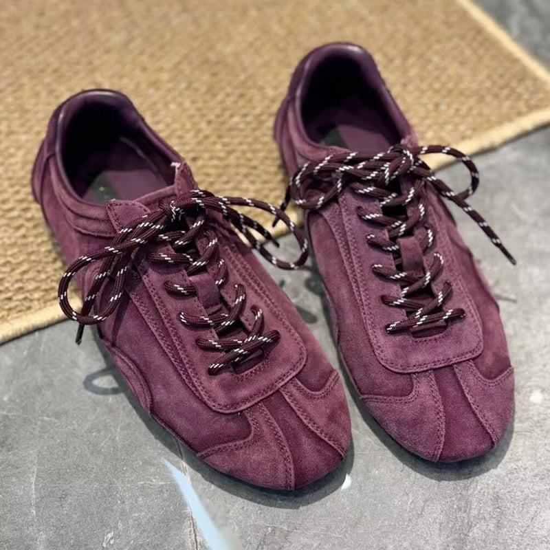 Close-up of burgundy suede sneakers showing thick patterned cords and padded collar