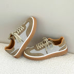 Beige and white sneakers on rug, displaying soft suede texture, mesh sections, and orange collar padding
