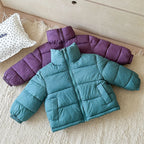 Purple and teal jackets laid flat on beige rug showcasing thick padding, zip closures, and side pockets.