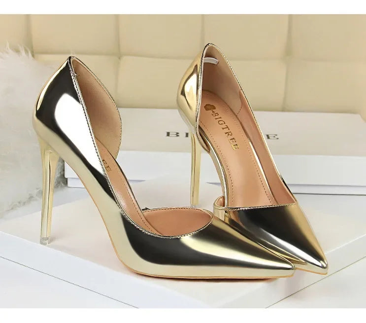 Glänzende metallische Gold-High Heels mit spitzem Zeh und dünnem Stilettoabsatz auf weißer Oberfläche, BIGTREE-Logo