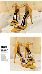 Saltos estilo gladiador amarelo mostarda com acabamento brilhante, bico aberto e fino salto stiletto dispostos em blocos brancos