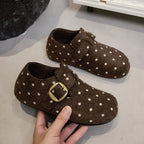 Primer plano de clogs de fieltro marrón chocolate con lunares blancos y hebillas doradas
