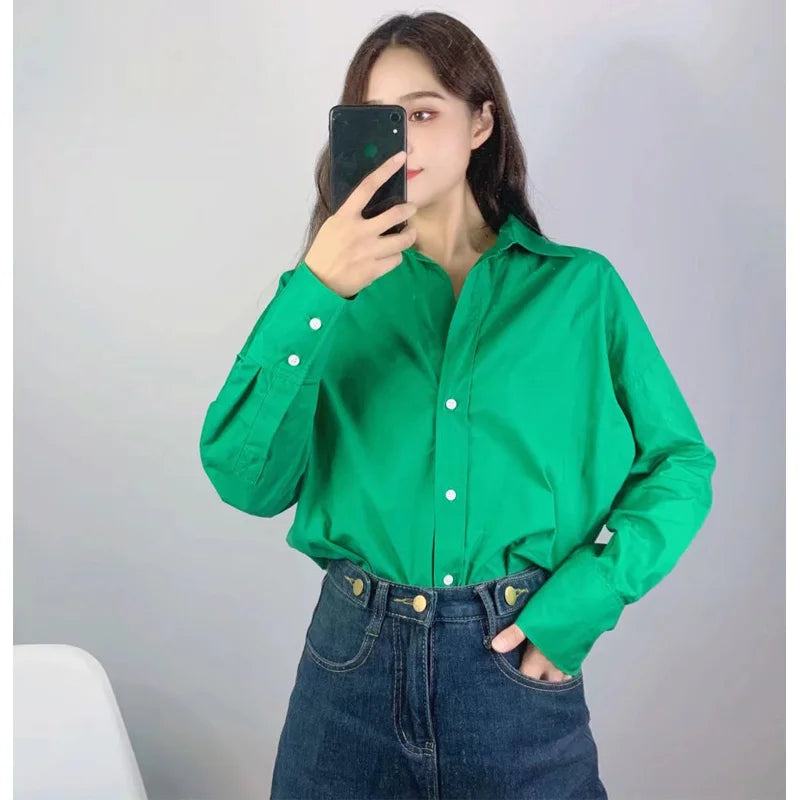 Selfie allo specchio di modella in camicia maniche lunghe verde smeraldo abbinata a jeans blu scuro