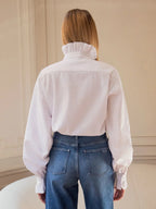 Rückansicht: Weißes Hemd mit sauberem Rückenpanel und hohem Rüschenkragen über blauen Jeans sichtbar