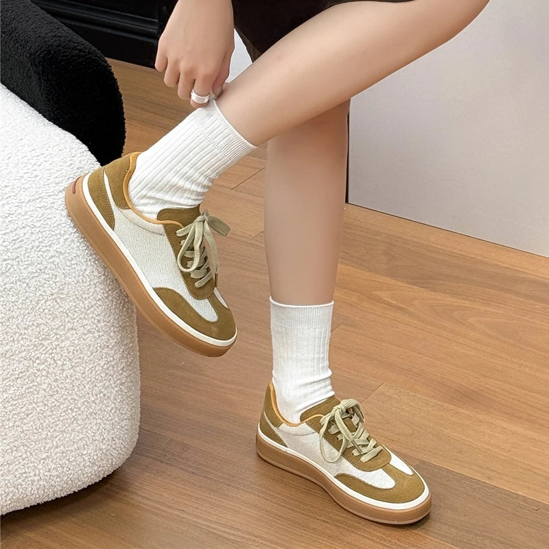 Woman wearing olive green and white patchwork sneakers with gum sole and white ribbed socks on sofa
