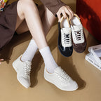 Modelo sostiene zapatillas negras y marrones mientras usa versión blanca con calcetines acanalados cerca de libros decorativos