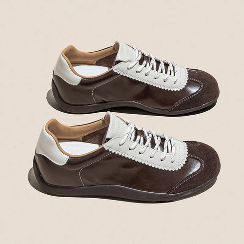 Zapatillas retro de cuero dividido y ante marrón oscuro con ojales dentados y cordones blancos sobre fondo beige