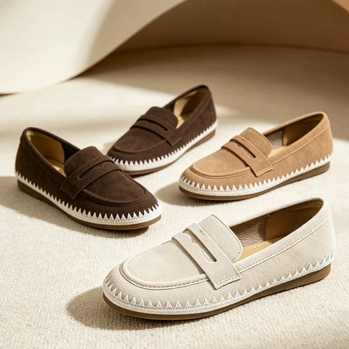 Dark brown, tan, and cream suede loafers scattered on a beige rug under warm lighting