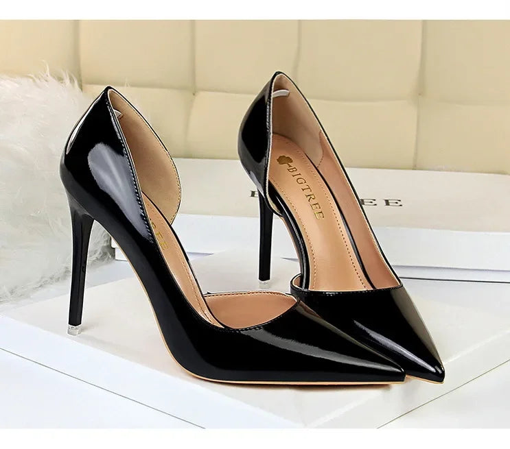 Nahaufnahme glänzender schwarzer High Heels mit spitzem Zeh und offenem Seitenbereich, BIGTREE-Logo auf beiger Innensohle sichtbar