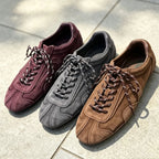 Three retro sneakers in burgundy, grey, and tan on grey tiles with white laces