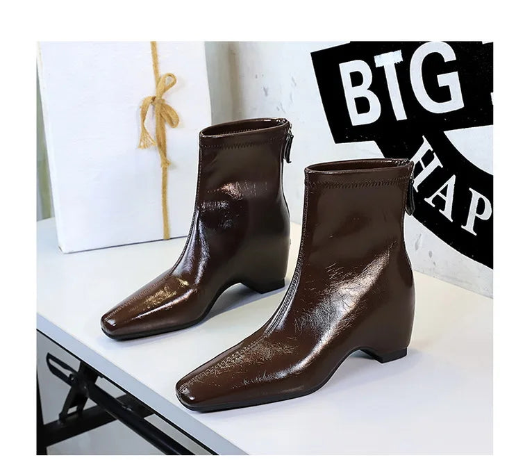 Botas escuras marrons desgastadas com bico quadrado e zíper traseiro em suporte de exibição