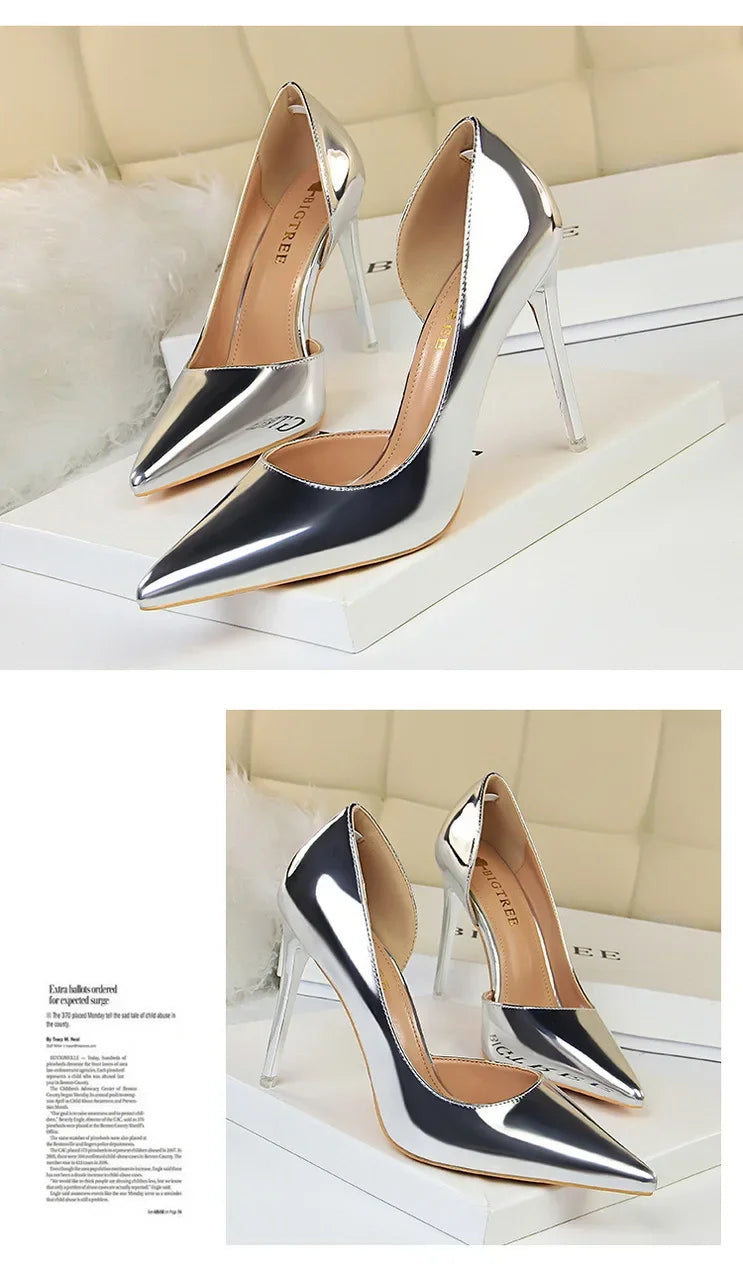 Silberne pointed-toe Pumps mit transparenten Stilettoabsätzen auf weißen Boxen vor beige gestepptem Hintergrund, Vorder- und Seitenansicht
