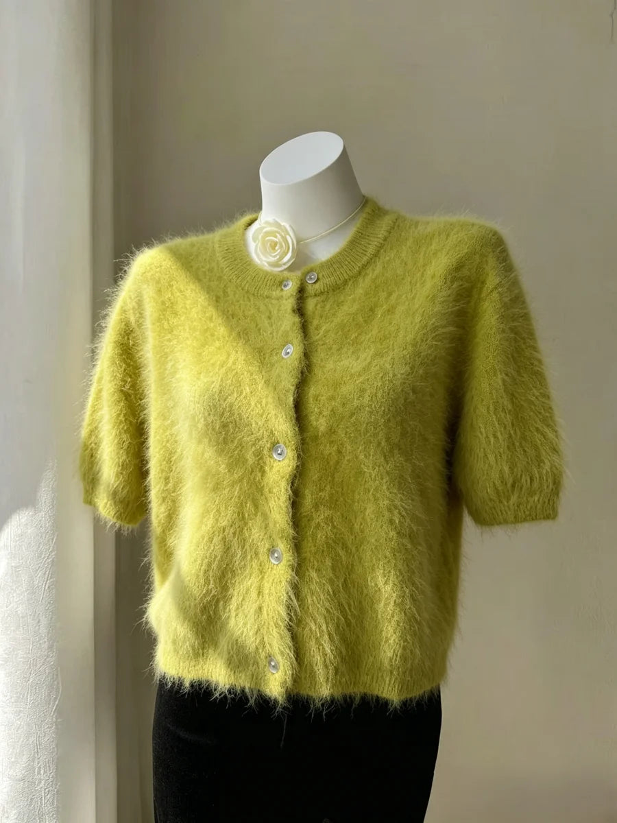 Cardigan curto felpudo verde-lima em torso de manequim com gola redonda, botões brancos e acessório de flor decorativa