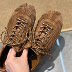 Hand holding tan brown suede sneaker showing cow leather texture and paneling