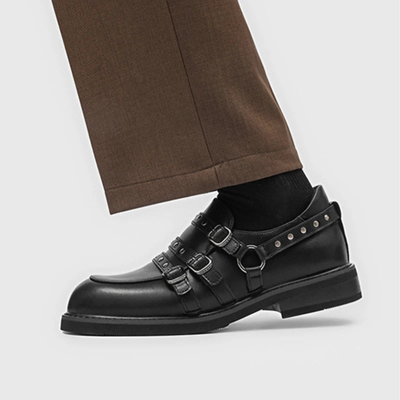 Seitenprofil schwarzer Loafer mit dreifachem Gurtschnallen und genietetem Knöchelring, getragen mit schwarzen Socken