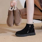 Modelo sosteniendo botas de ante marrones mientras usa la versión negra, mostrando suela gruesa de goma y diseño de cremallera lateral