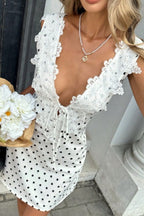 Gepunktetes Minikleid mit weißer Blumenstickerei, tiefer V-Ausschnitt zum Binden, ärmellos, rückenfrei