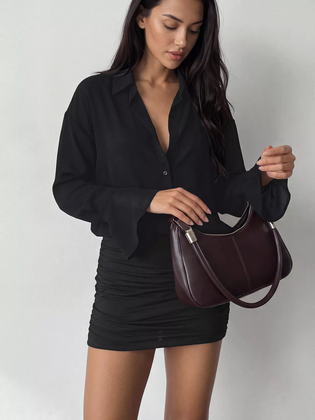 Gros plan haut de robe noire : V déboutonné, drapé tissu et poignet structuré