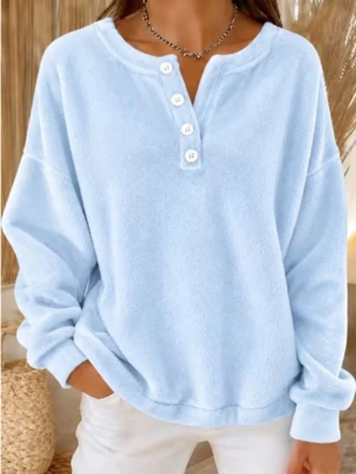 Sweat boutonné bleu pastel aux épaules tombantes, stylisé avec un jean blanc