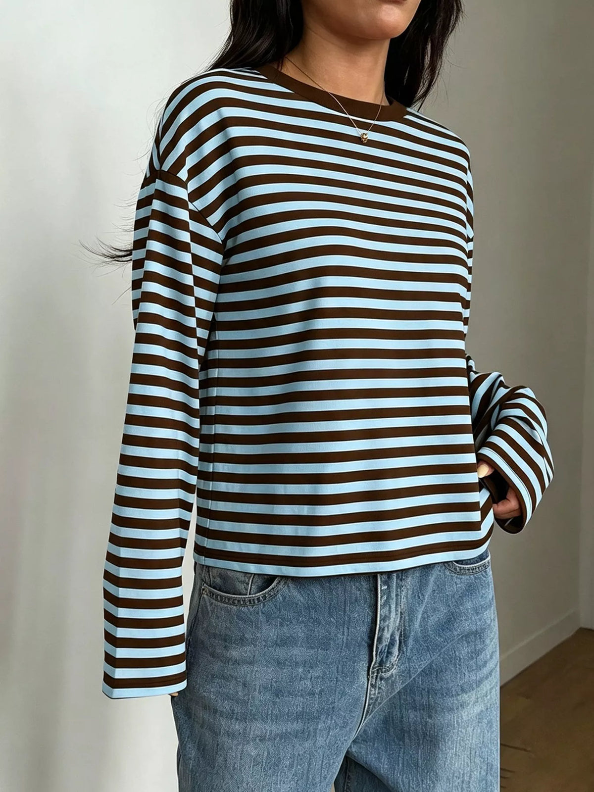 Angolo tre quarti maglietta a righe marrone e azzurro inserita nei jeans blu che dimostra lunghezza manica e profilo laterale
