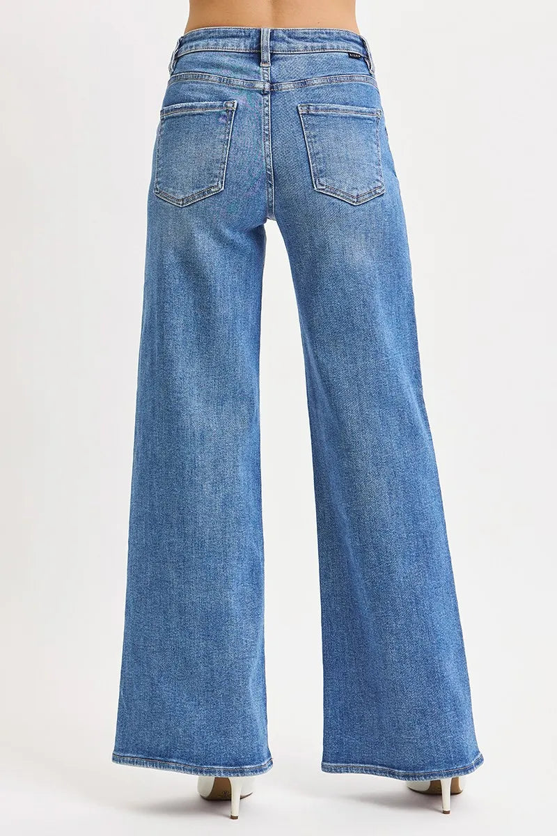 Back view of wide-leg jeans displaying patch pockets, centered seam, and black waistband label maintaining structured shape