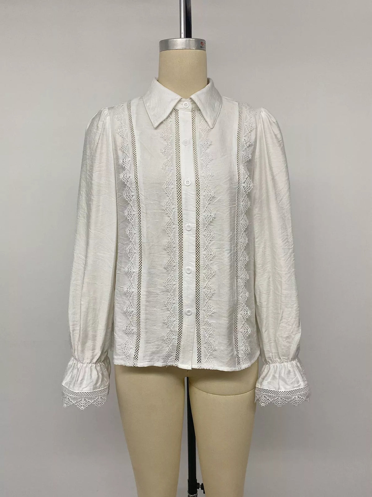 Vollbild Produktfoto weißes Bluse auf Mannequin, zeigt lockeren Schnitt, Bischofärmel und symmetrische Spitzenpanels.