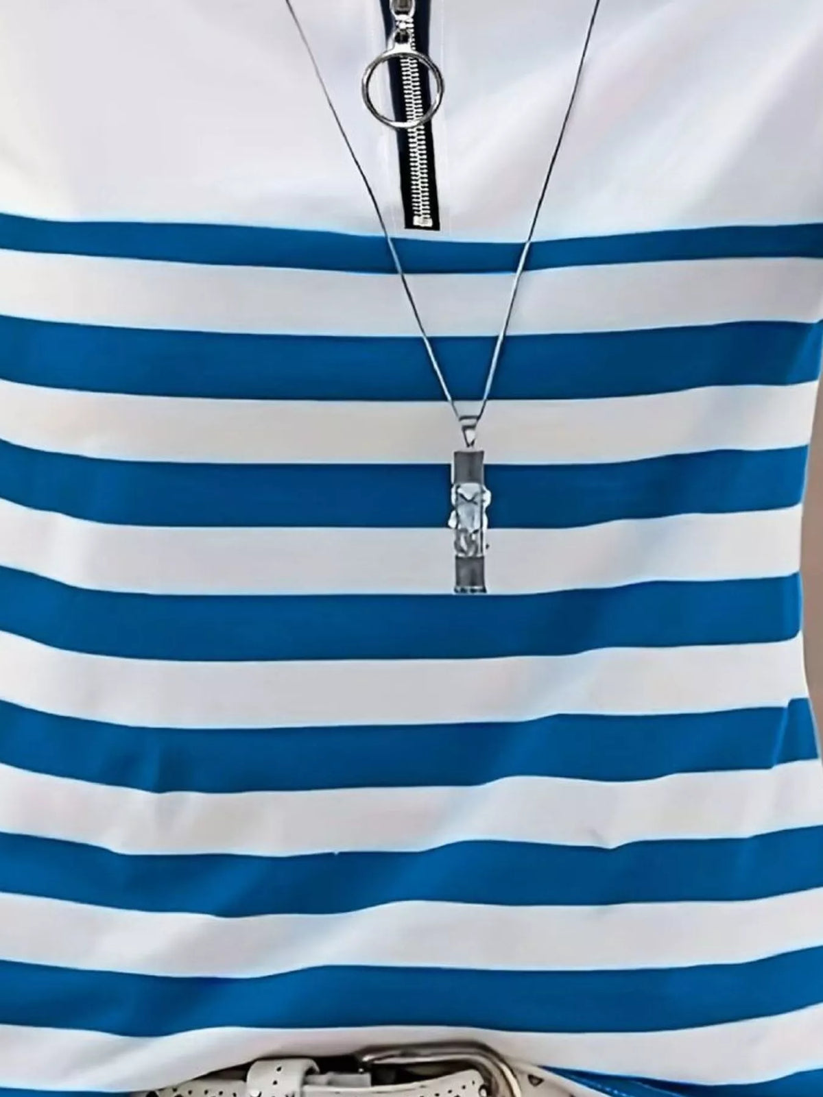 Close-up of blue and white striped top featuring large circular zipper pull tab